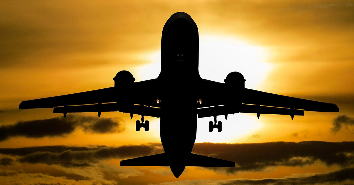 Imagen de un avión con el sol de fondo que simboliza el transporte internacional refrigerado, servicio que ofrece la división de transporte de Grupo Caliche